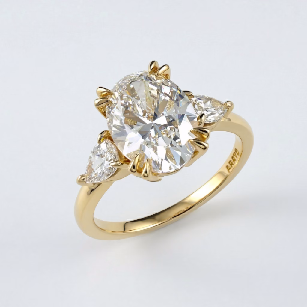Three-stone 14K yellow gold diamond ring by Arato showcasing a large oval-cut center diamond and two brilliant pear-shaped side stones.