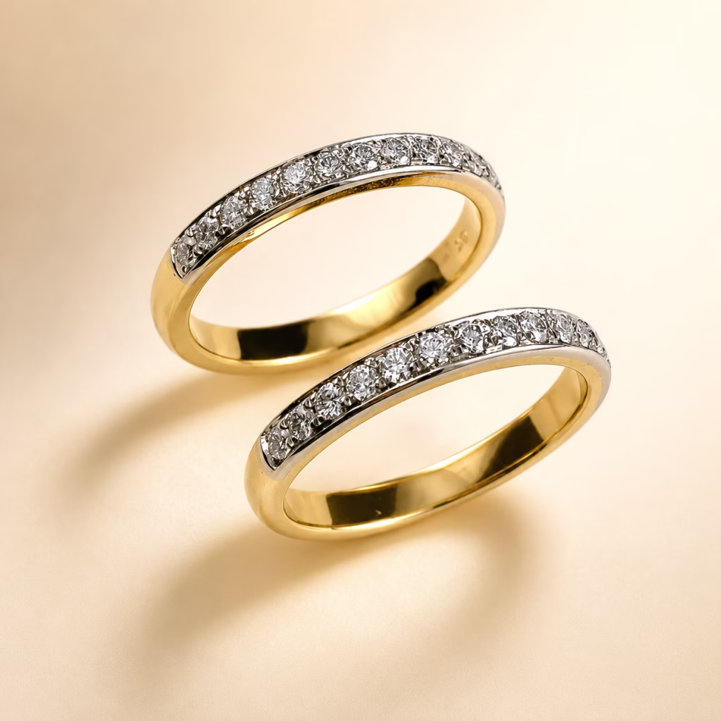 Two yellow gold diamond bands with pavé diamond details on a cream studio background.